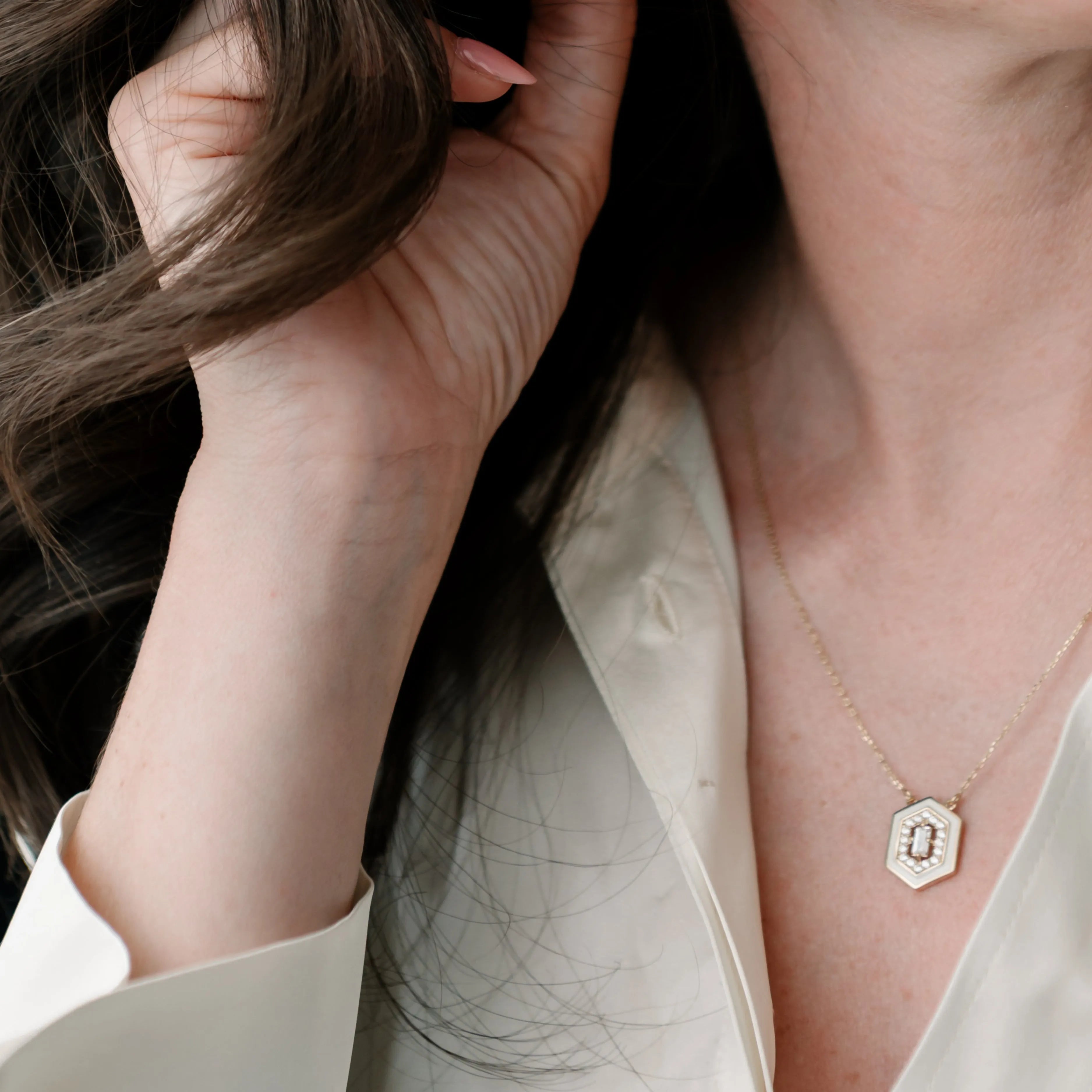 Žena v bielej blúzke nosí zlatý náhrdelník s geometrickým príveskom – CREYO GEOMETRIC