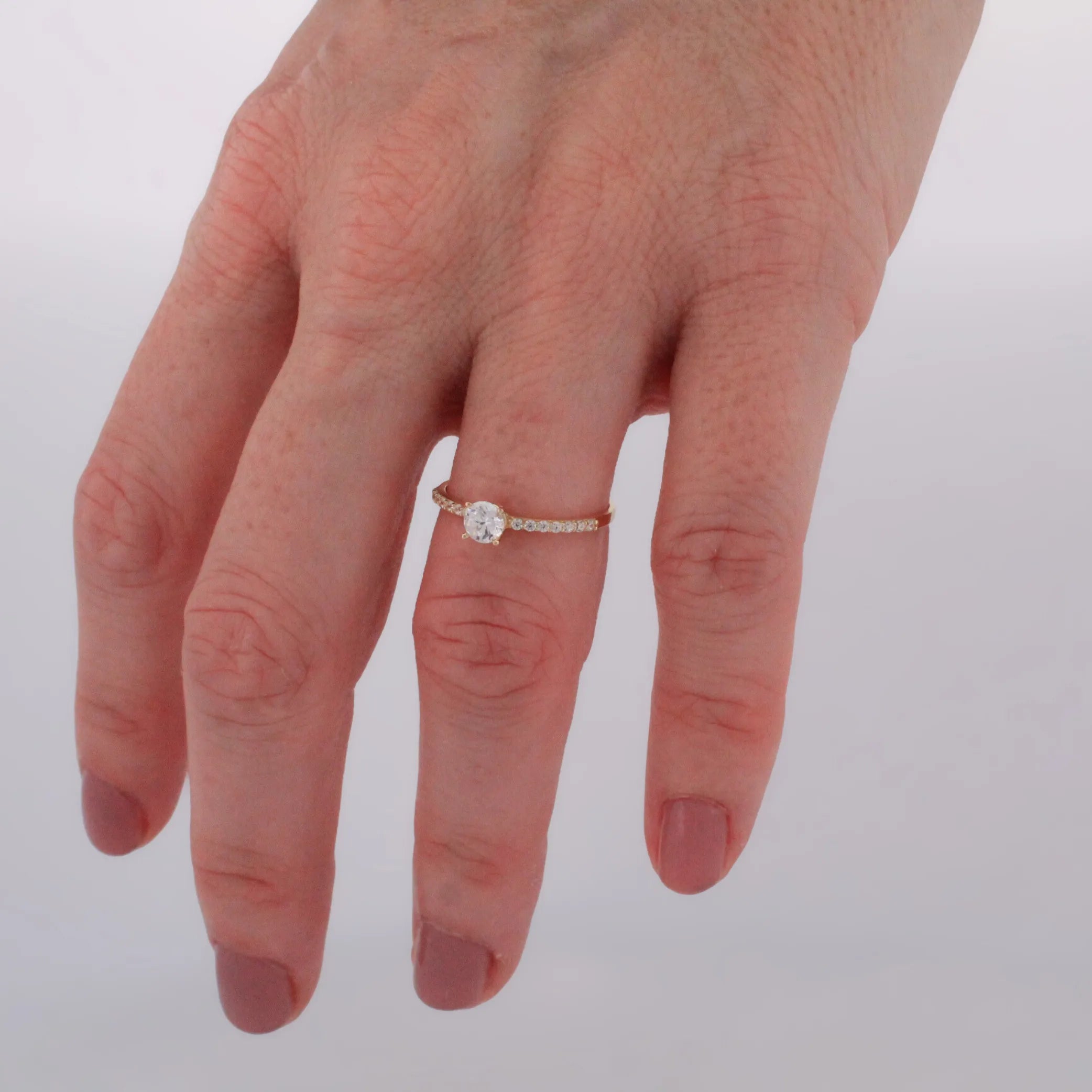 Zlatý prsteň STELLA so zirkónom pri prirodzenom svetle na ženských rukách.