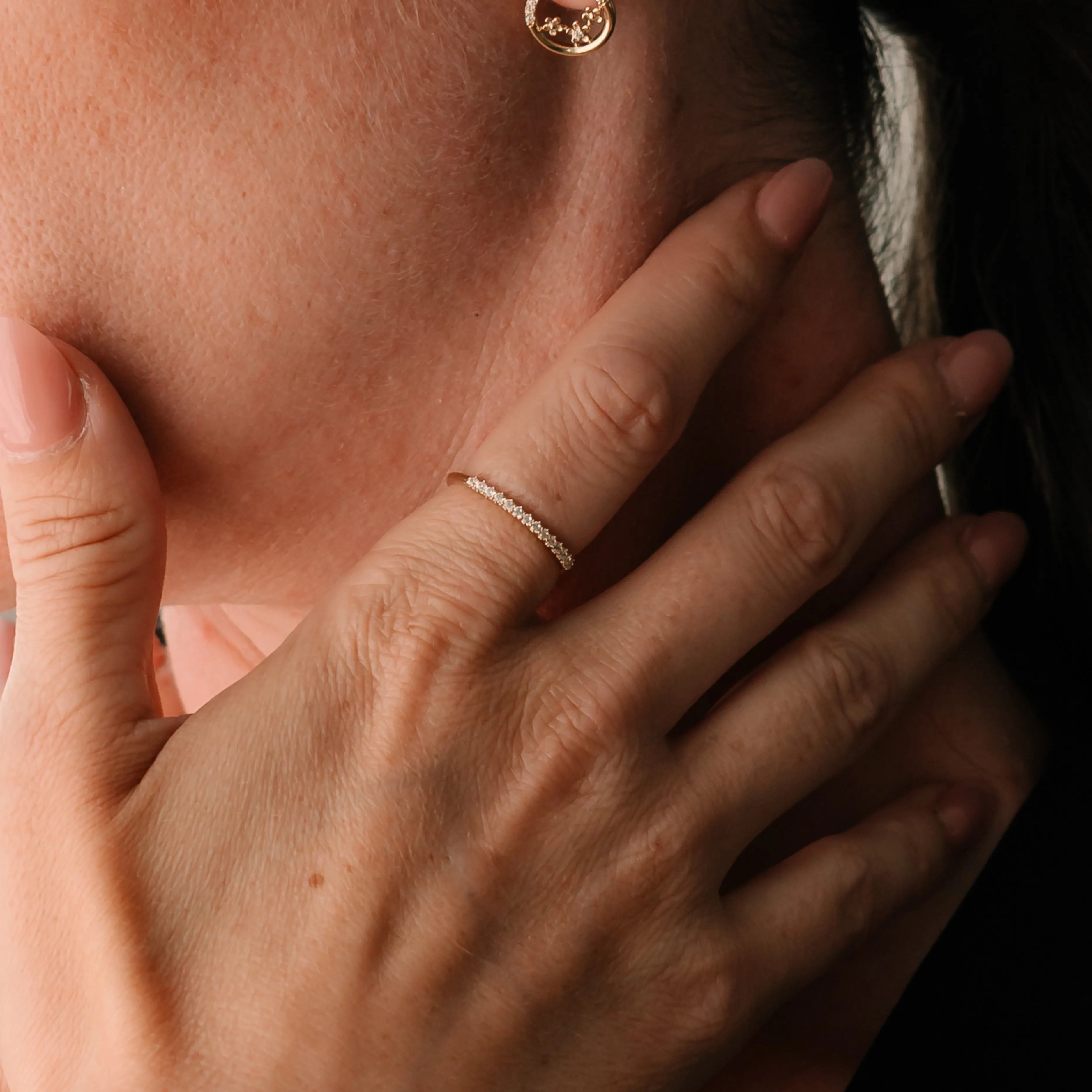 Detail ruky ženy s jemným prsteňom zo žltého zlata osadeným zirkónmi – CREYO LINEA